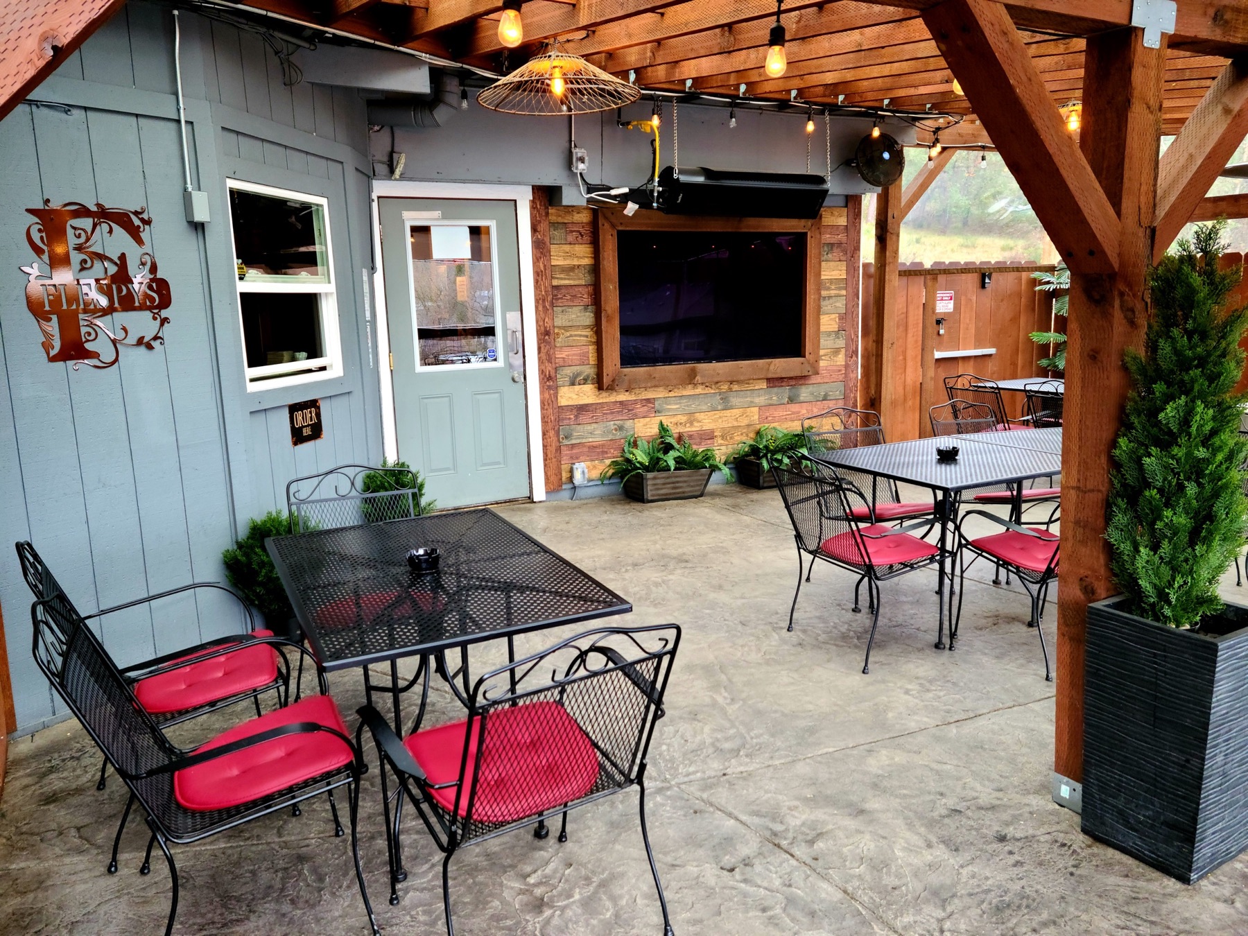 Covered patio seating, string lights, and television at Flespy’s
